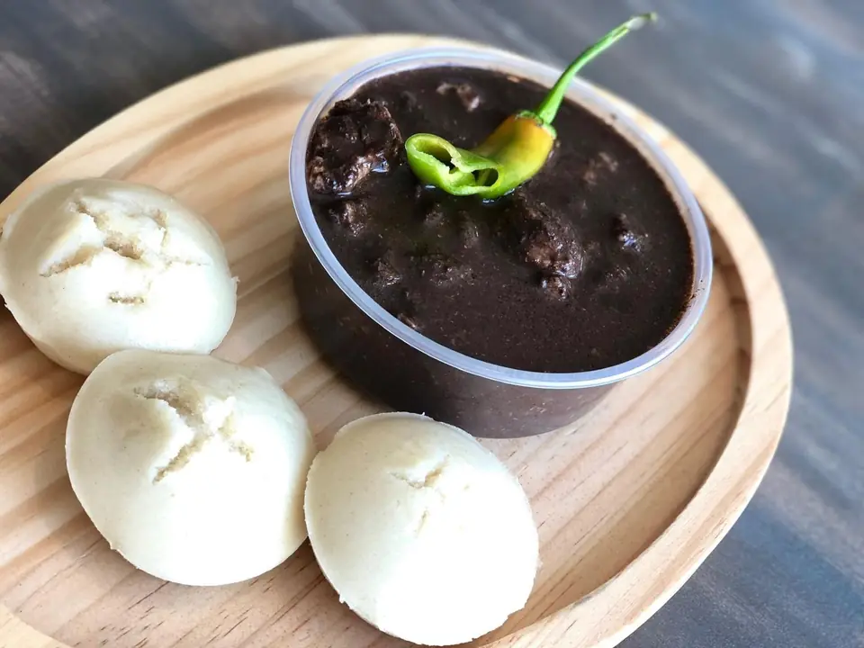 Dinuguan with puto rice cakes on a wooden plate